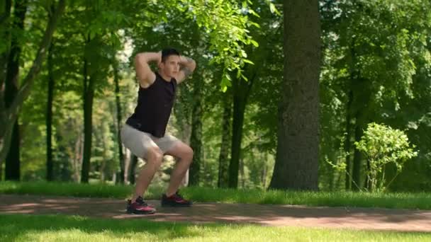 Aptidão exterior. Treino de ginástica no parque. Um homem a fazer agachamentos. Encaixe homem agachar — Vídeo de Stock