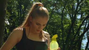 Susamış kadın açık spor şişe su ile. Plastik şişe tutan yorgun kadın