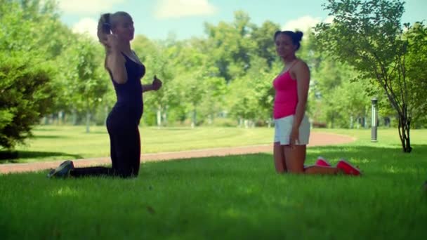 Молодая женщина разговаривает на коленях на зеленой траве в парке — стоковое видео