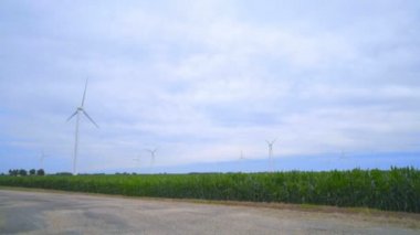 Wind turbines farm. Wind generators landscape. Rustic road under clouds sky