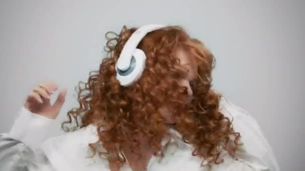 Захоплена жінка слухає музику в навушниках. усміхнена дівчина танцює в навушниках — стокове відео