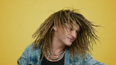 Sarı arka planda dans eden neşeli rockçı. Gülümseyen adam başını sallıyor.