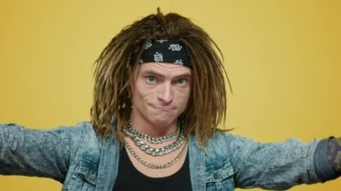 Saç bantlı şık rock 'çı ellerini kendine doğrultuyor. Elleriyle hareket eden adam.