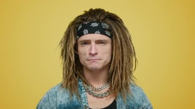 Ciddi bir rockçı kameraya bakıyor. Stüdyoda kendini gösteren bir adam.