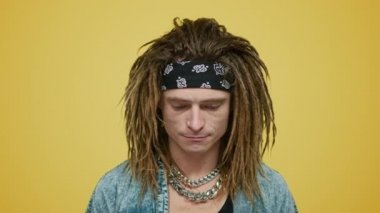 Şık bir adam sarı arka planda kafasını kaldırıyor. Dur işareti gösteren adam