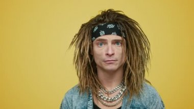 Sarı arka planda şaşırmış bir adam yüzü. Saç bandı takmış rock 'çı.