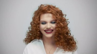 Gri arka planda poz veren mutlu kadın. Yakından güzel bir kız kameraya gülümsüyor