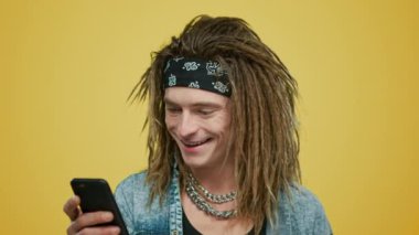 Sarı arka planda akıllı telefon kullanan bir adam. Hipster cep telefonu ekranına bakıyor