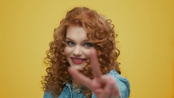 Woman showing v sign on yellow background. Lady showing peace sign with hand — Stock Video