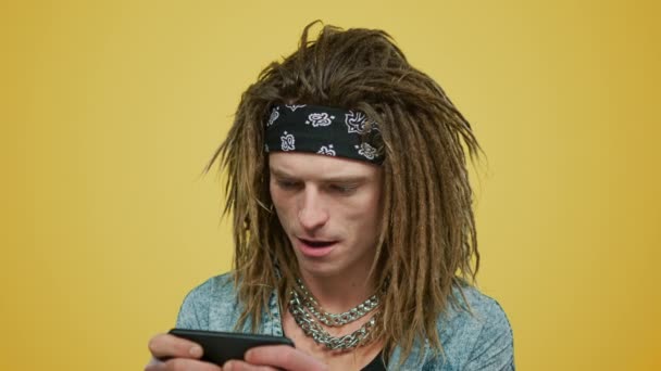 Homem jogando jogo no smartphone. Cara usando celular no fundo amarelo — Vídeo de Stock