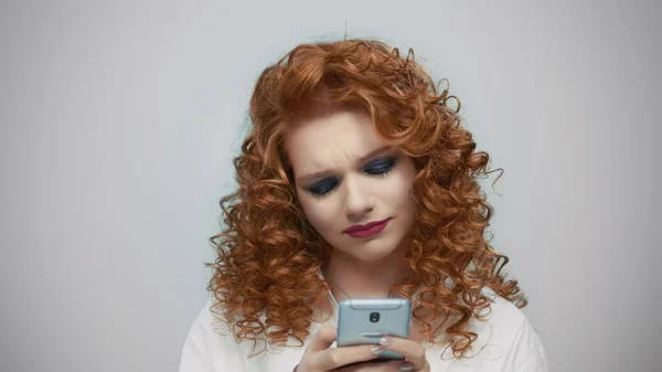 Mujer escribiendo en el teléfono inteligente en el fondo gris. Chica usando el teléfono móvil —  Fotos de Stock