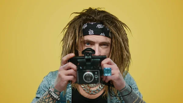 Мужчина фотографирует на старую фотокамеру. Улыбающийся парень позирует перед камерой в студии — стоковое фото