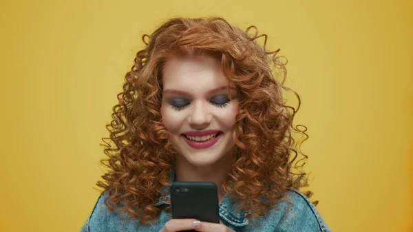 Mulher usando smartphone no fundo amarelo. Menina digitando mensagem no telefone — Fotografia de Stock