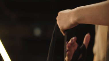 Kimliği belirsiz bir kadın spor salonunda dövüşmeye hazırlanıyor. Elleri saran kadın.