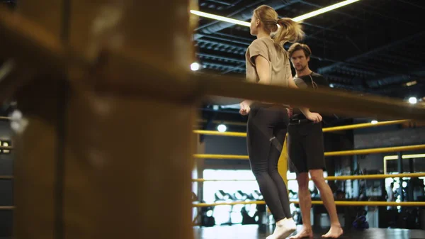 Chica enérgica en forma saltando en la cuerda en el gimnasio. El entrenador cuenta saltos en el ring — Foto de Stock