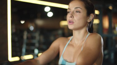 Beden eğitiminde simülatör kullanan seksi bir kız. Spor kulübünde kol egzersizi yapan bir kadın.