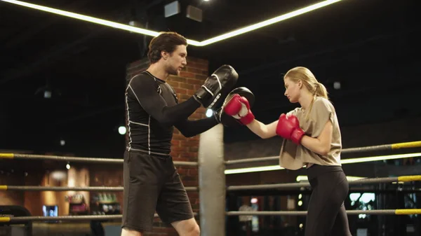 Vážný boxer poučující boxerku o boxerském ringu. Sportovní pár v posilovně — Stock fotografie