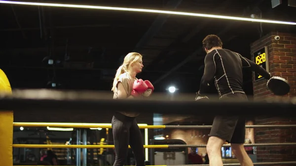 Guapo entrenador de enseñanza en forma chica en el club deportivo. Boxeo de mujer deportiva en el gimnasio — Foto de Stock