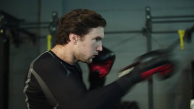 Spor salonunda tekme pratiği yapan endişeli bir sporcu. Erkek boksör spor kulübünde ısınıyor.