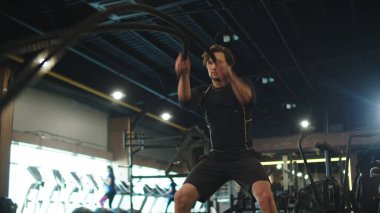 Spor salonunda halat kullanan formda bir adam. Spor adamı kulüpte tekrarlar yapıyor.