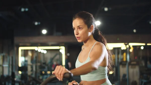 Chica deportiva calentándose en el gimnasio. Mujer fitness usando velosimulador en club deportivo — Foto de Stock