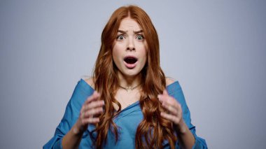 Stüdyoda kafası tutulan şok olmuş bir kız. Gri üzerinde poz veren hayal kırıklığına uğramış kadın.