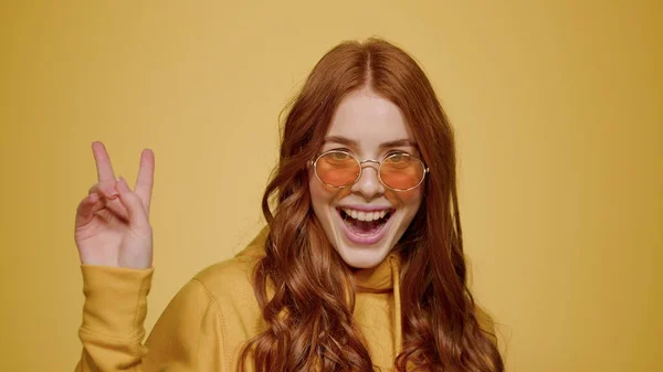 Leuke vrouw met vredesteken in de studio. roodharige meisje vieren overwinning binnen — Stockfoto