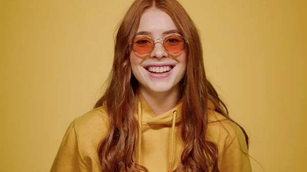Una chica encantadora sonriendo en el estudio. Mujer posando en la lente sobre fondo naranja — Foto de Stock