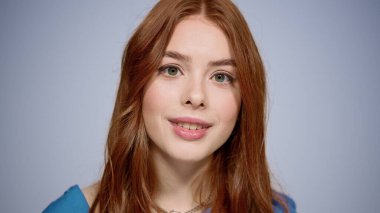 Stüdyoda el hareketi yapan neşeli bir kız. Kapalı mekanda yüzüne dokunan bir kadın.