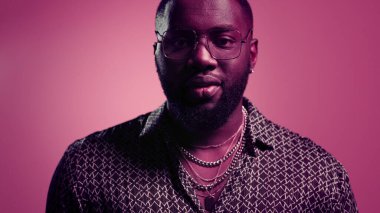 Stüdyoda kameraya gülümseyen Afrikalı Amerikalı bir adam. Kamerada poz veren disko elemanı