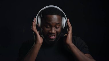 İçeride kulaklık takan Afro oyuncu. Adam stüdyoda müzik dinliyor.