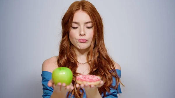 Fille douteuse qui prend une décision en studio. Femme souriante choisissant la pomme à l'intérieur — Photo