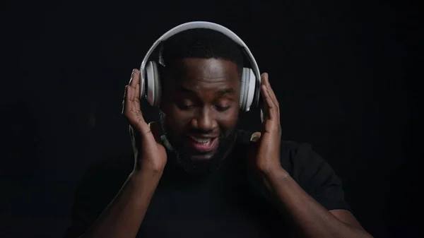 Un chico afro juguetón usando auriculares adentro. Hombre escuchando música en estudio —  Fotos de Stock