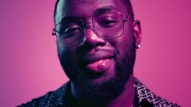 Afrikalı Amerikalı adam stüdyoda öpüşüyor. Kapalı alanda merceğe bakan süslü adam.