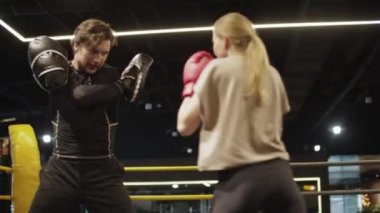 Koçla boks ringinde arkadaş canlısı formda kız eğitimi. Spor salonunda kadın boksör.