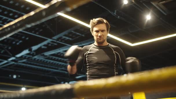 Hombre deportivo agitado preparándose para el boxeo en el gimnasio. Ajuste hombre golpeando puños en el anillo — Vídeo de stock
