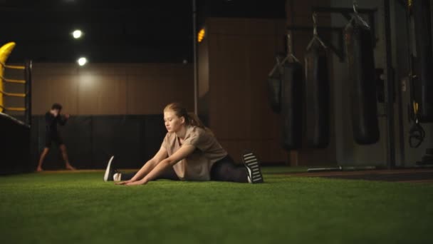 En energisk idrottskvinna som delar sig på idrottsklubben. Passform flicka uppvärmning på gym — Stockvideo