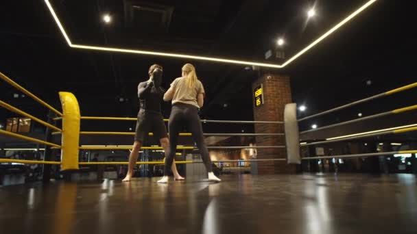 Fille en forme focalisée frappant des coussinets de poinçonnage dans le club de sport. boxer féminin séance d'entraînement — Video