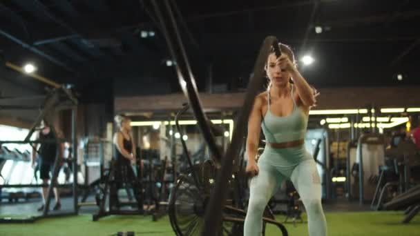 Trött kvinnlig idrottare avslutande träning i sport klubb. Passform flicka träning på gym — Stockvideo