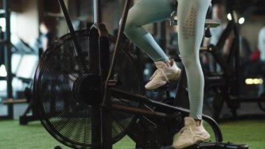 Sportif kız spor salonunda ısınıyor. Spor kulübünde spor bisikleti kullanan bayan sporcu