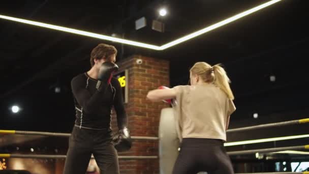 ジムで戦うアクティブなスポーツカップル。コーチトレーニングフィット女の子オンボクシングリング — ストック動画
