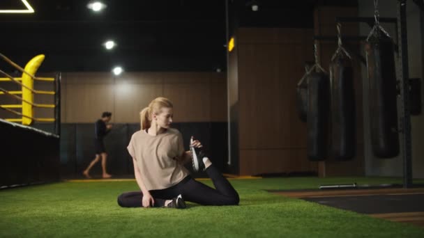 Allvarlig kvinnlig boxare som stretchar i sportklubben. Passform flicka träning på gym — Stockvideo