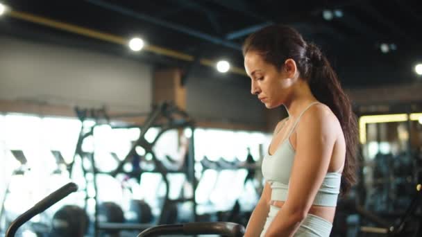 En utmattad tjej som sitter i sportklubben. Sport kvinna gör paus på gymmet — Stockvideo