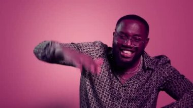 Kapalı mekanda şarkı söyleyen mutlu afro adam. Pembe arka planda dans eden yakışıklı erkek.