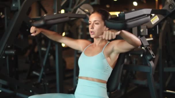 Ragazza sportiva che fa i riccioli delle braccia in palestra. Donna che fa esercizio nel centro fitness — Video Stock