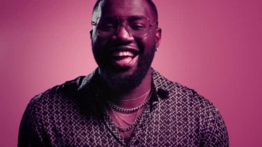 Kapalı alanda gülen mutlu afro adam. Pembe arka planda kıkırdayan erkek.
