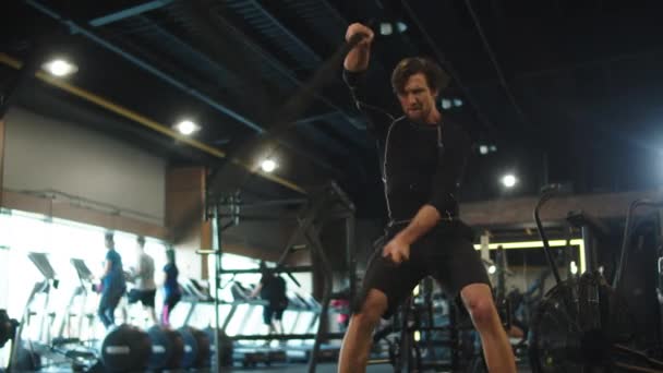 Energetic athlete using battle ropes at gym. Sport man doing repetitions in club — Stock Video