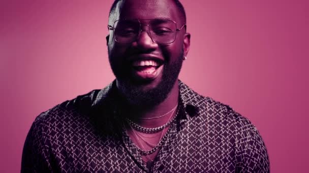 Un tip afro fericit râzând în interior. Bărbat chicotind pe fundal roz — Videoclip de stoc
