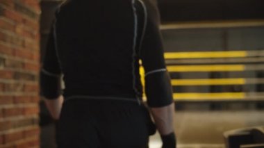 Spor kulübünde merdivenlerden çıkan kimliği belirsiz bir adam. Boksör ring iplerinden geçiyor