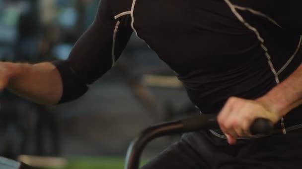 En utmattad idrottsman som värmer upp på en cykel på gymmet. Passform man gör cardio på gym — Stockvideo